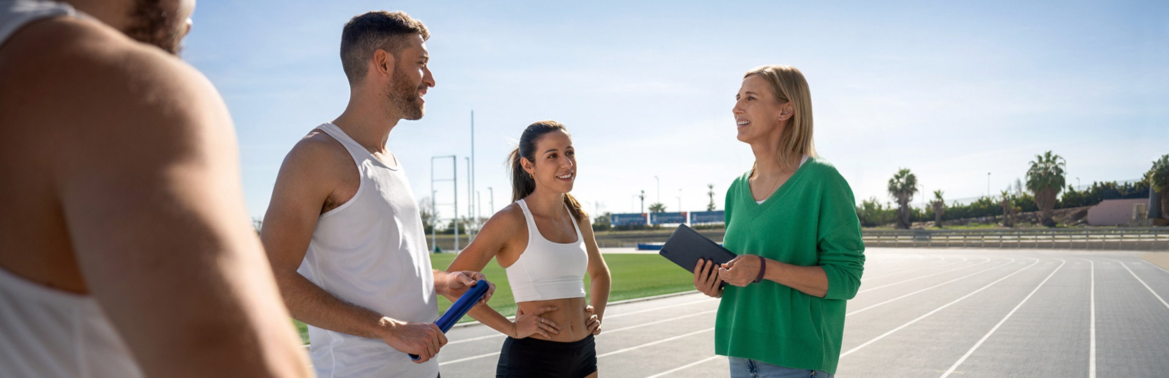 Sportpsychologin und Mental Coach Anett Szigeti im Gespräch mit Athleten auf einer Laufbahn.